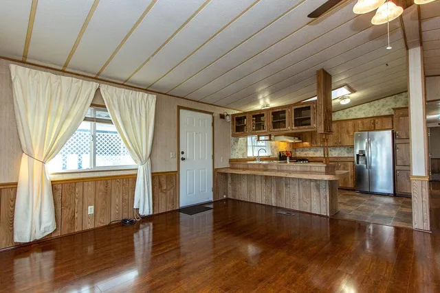 a kitchen with stainless steel appliances granite countertop a refrigerator a sink dishwasher a stove and white countertops with wooden floor