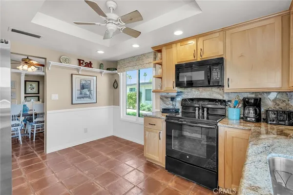 a kitchen with stainless steel appliances granite countertop a stove top oven a sink dishwasher a dining table and chairs with wooden floor