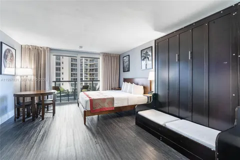 a spacious bedroom with a bed a table and wooden floor