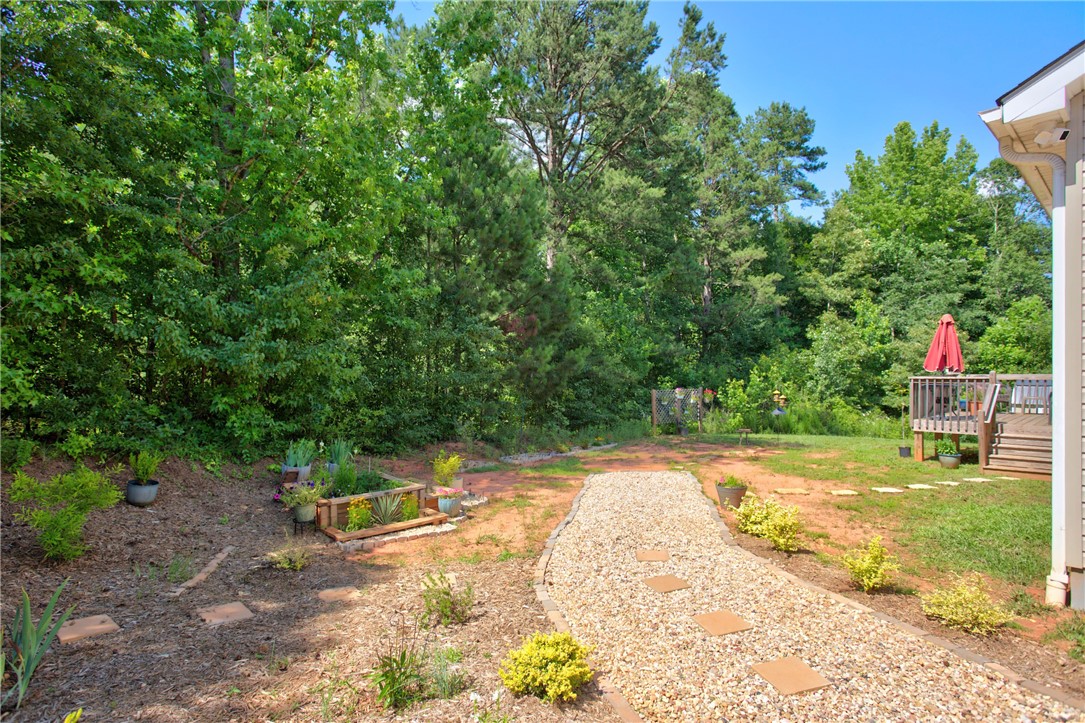 405 Pawnee Drive Walhalla, SC 29691 - Photo 23 of 36 A verdant backyard with a gravel path leads to a charming wooden deck.