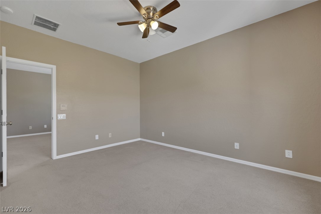 2501 Bechamel Place Henderson, NV 89044 - Photo 28 of 50 An airy bedroom with carpeted floors and a ceiling fan, offering a tranquil retreat.