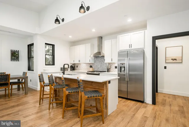 a kitchen with stainless steel appliances granite countertop a dining table chairs refrigerator sink and cabinets