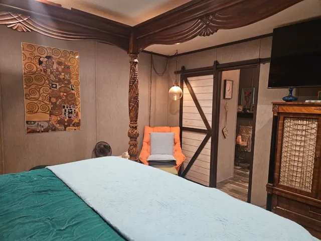 a bedroom with a bed and a flat tv screen on the dresser