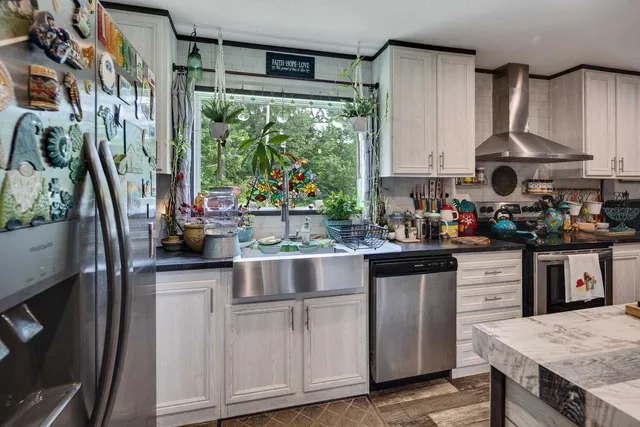 a kitchen with stainless steel appliances granite countertop a sink a stove and a wooden floors