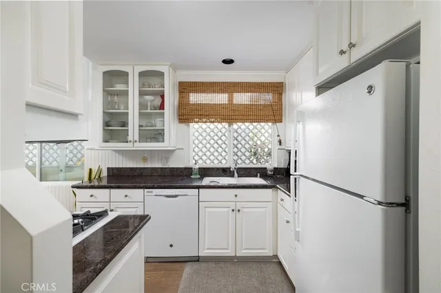 a kitchen with granite countertop a sink stove and refrigerator