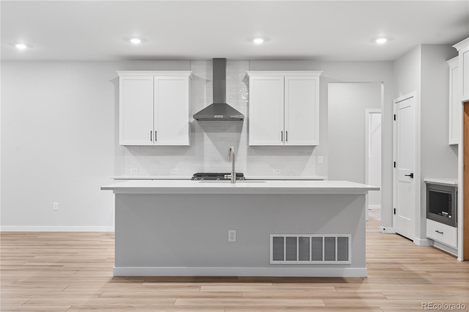 12051 Amplify Circle Lone Tree, CO 80134 - Photo 12 of 34 a kitchen with stainless steel appliances granite countertop a sink a stove a refrigerator and white cabinets with wooden floor