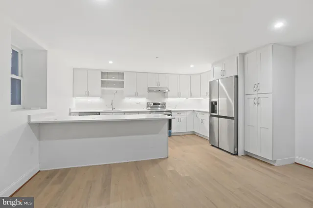 a kitchen with kitchen island white cabinets and refrigerator