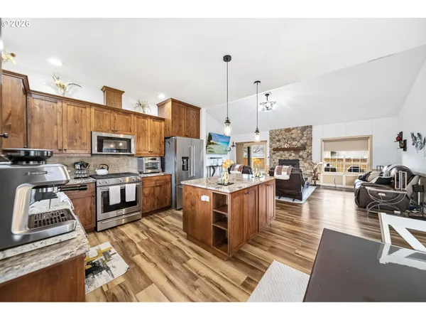 a kitchen with stainless steel appliances kitchen island granite countertop a refrigerator a stove a sink dishwasher and white cabinets with wooden floor