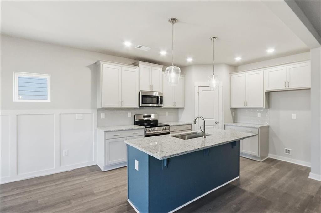 4057 Links Boulevard Jefferson, GA 30549 - Photo 12 of 58 a kitchen with a sink stove a refrigerator and white cabinets with wooden floor