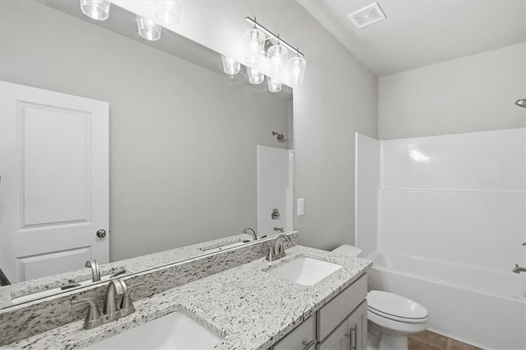 4057 Links Boulevard Jefferson, GA 30549 - Photo 26 of 58 a bathroom with a granite countertop sink a toilet and a large mirror
