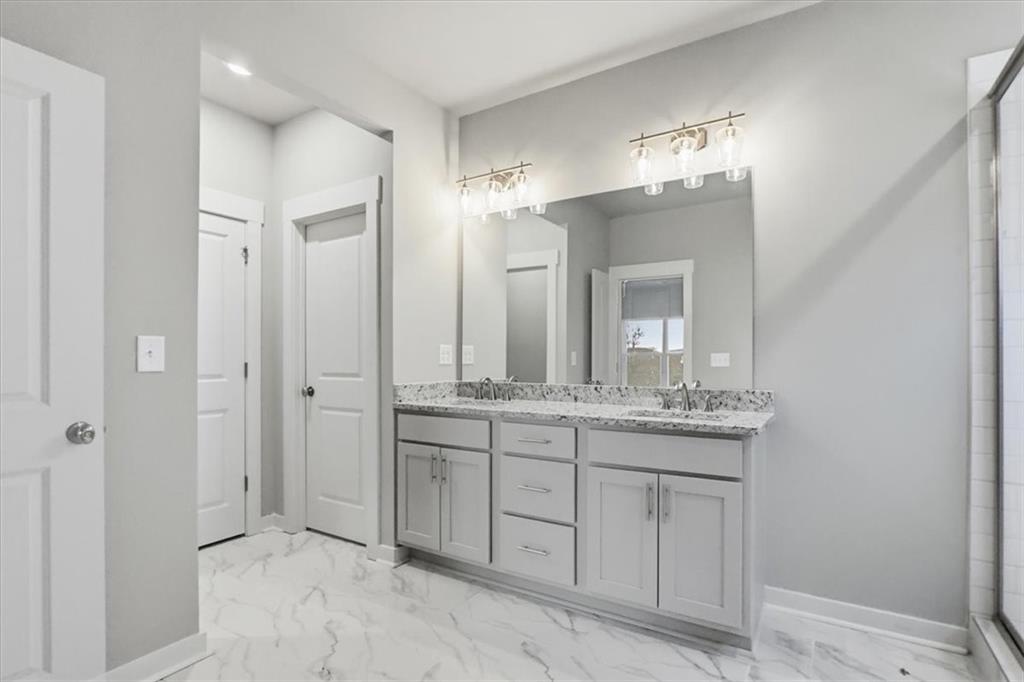 4057 Links Boulevard Jefferson, GA 30549 - Photo 35 of 58 a bathroom with a granite countertop sink a mirror and a shower