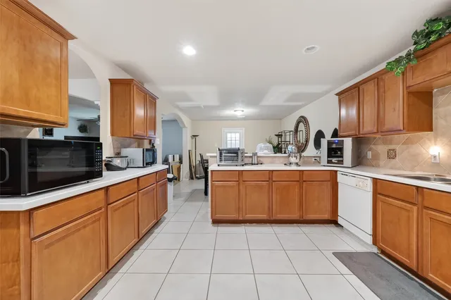 a large kitchen with stainless steel appliances granite countertop a large stove top oven a sink dishwasher and white cabinets