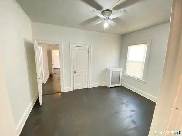 an empty room with windows and fan