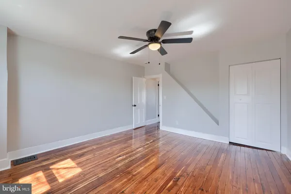 a view of empty room with wooden floor and fan