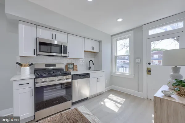 a kitchen with stainless steel appliances granite countertop a stove a sink and a microwave