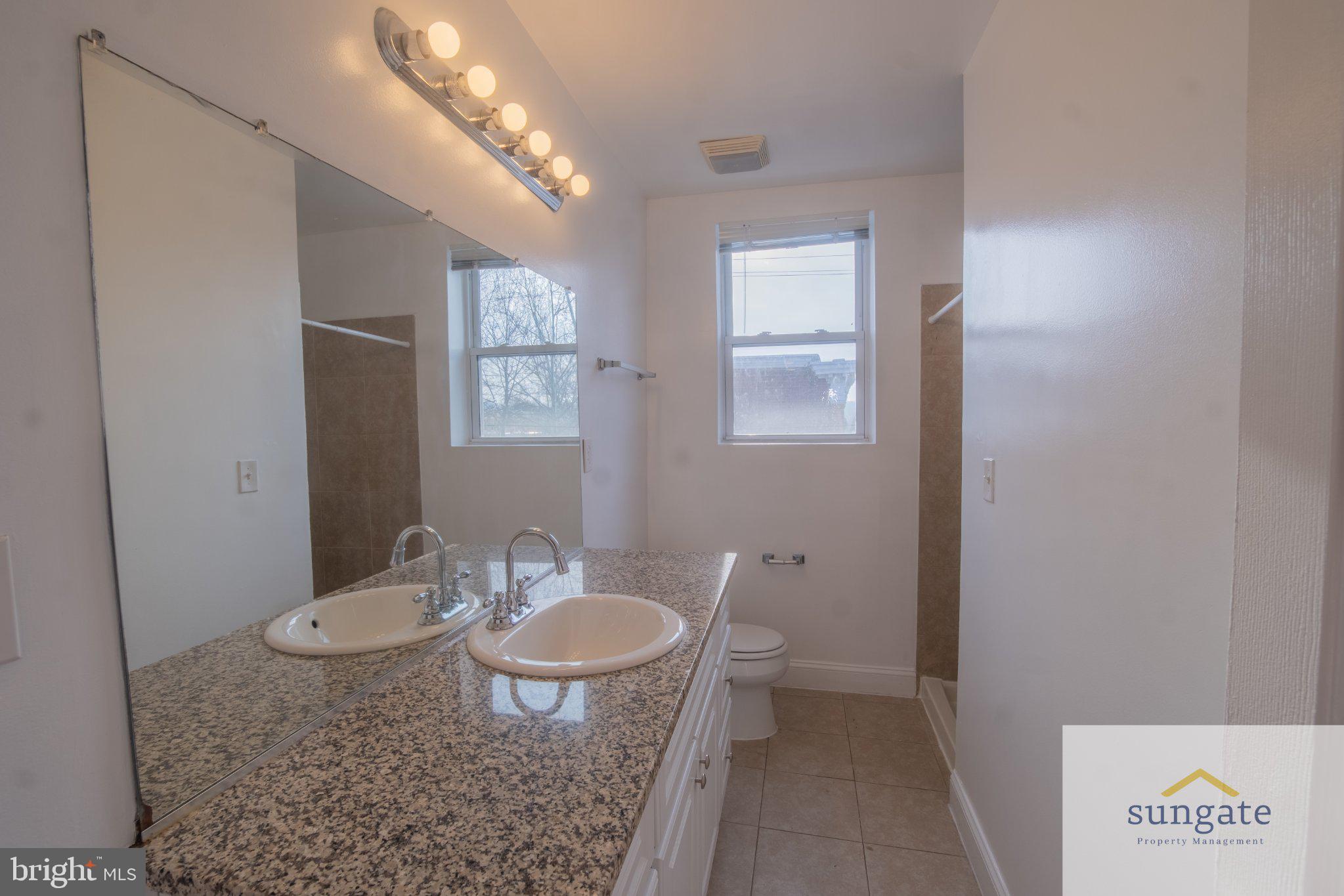 4032 Falls Road, Unit 2 Baltimore, MD 21211 - Photo 6 of 30 a bathroom with a granite countertop sink toilet a mirror and vanity