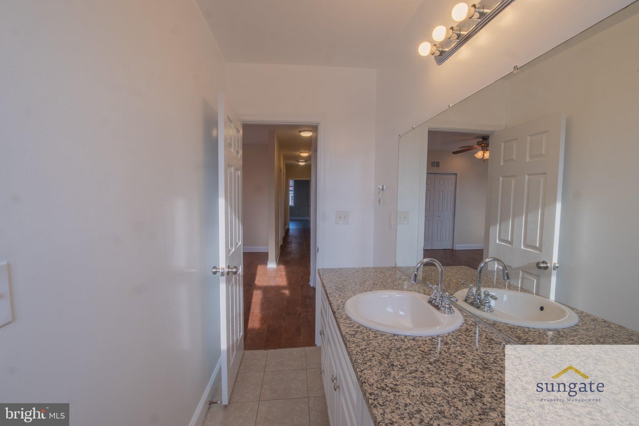 4032 Falls Road, Unit 2 Baltimore, MD 21211 - Photo 7 of 30 a bathroom with a granite countertop sink a mirror and shower