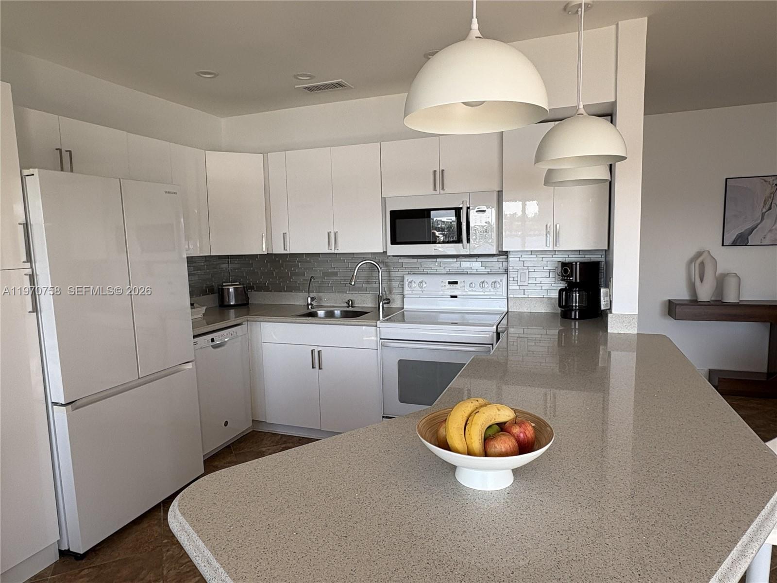 1201 South Riverside Drive, Unit 107 Pompano Beach, FL 33062 - Photo 10 of 27 a kitchen with stainless steel appliances granite countertop a refrigerator a stove a sink dishwasher and white cabinets with wooden floor