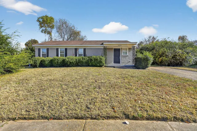 a front view of a house with a yard and potted plants
