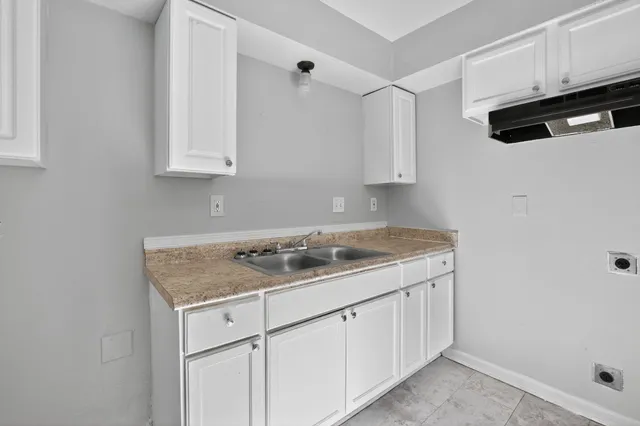 a kitchen with white cabinets and sink