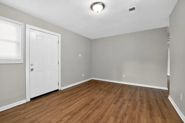 an empty room with wooden floor and windows
