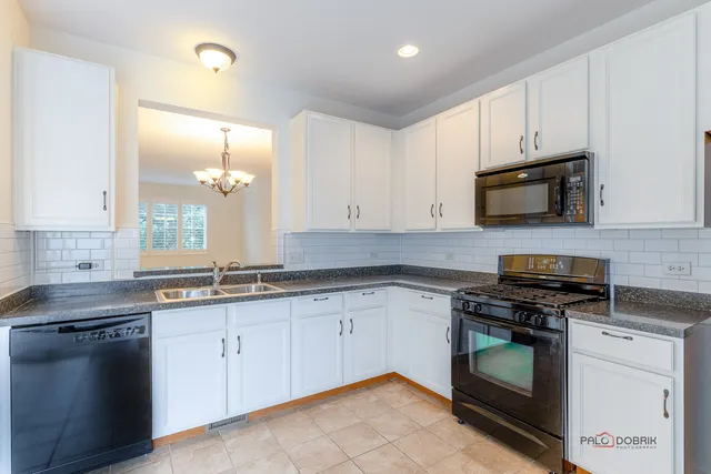 a kitchen with granite countertop white cabinets sink and stainless steel appliances
