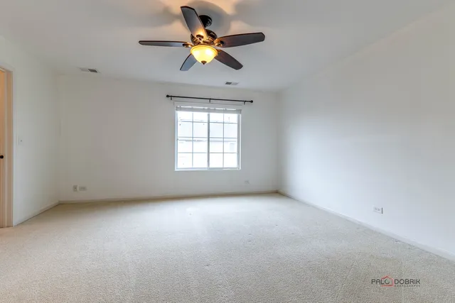 an empty room with a window and a ceiling fan