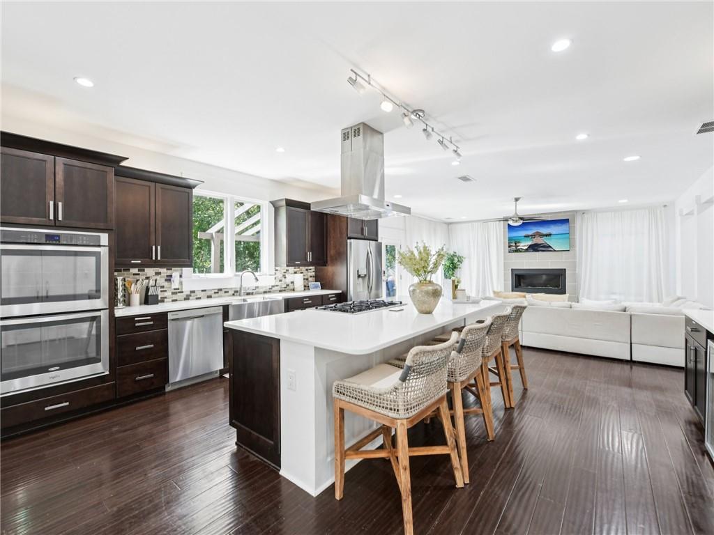1399 North Druid Hills Road Northeast Atlanta, GA 30319 - Photo 16 of 58 a kitchen with stainless steel appliances kitchen island granite countertop a stove a sink dishwasher a dining table and chairs with wooden floor