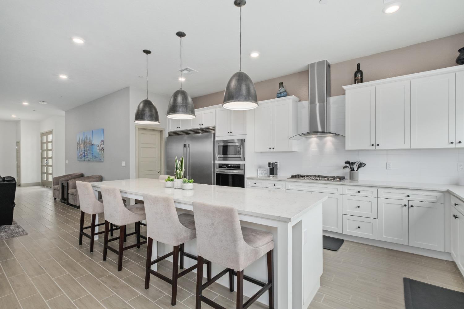 859 Maclure Avenue Madera, CA 93636 - Photo 13 of 53 a kitchen with stainless steel appliances kitchen island granite countertop a table chairs and white cabinets