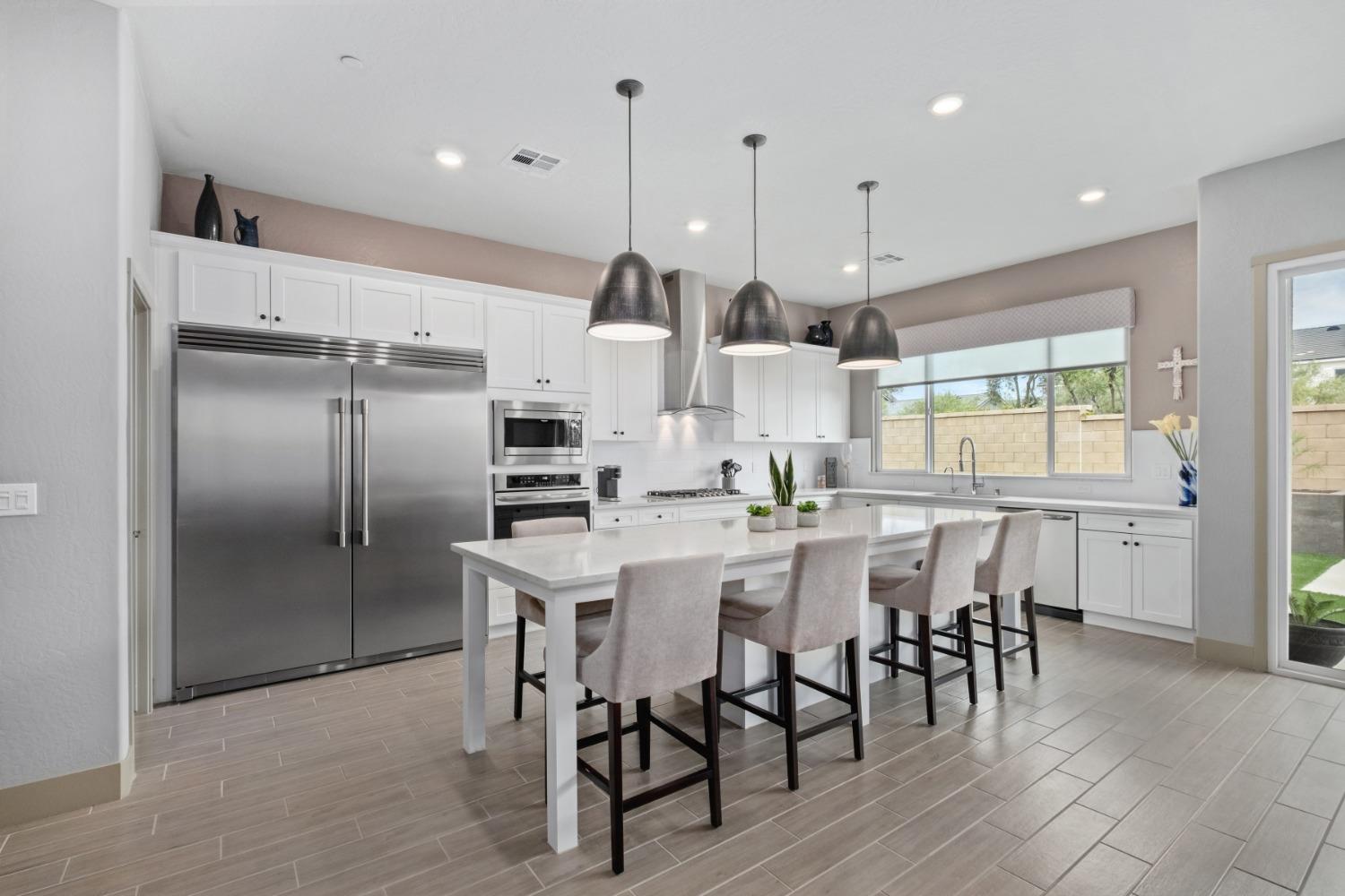 859 Maclure Avenue Madera, CA 93636 - Photo 14 of 53 a kitchen with stainless steel appliances kitchen island granite countertop a table chairs and a wooden floor