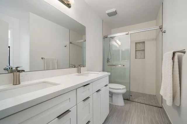 a bathroom with a sink a toilet a shower and a mirror