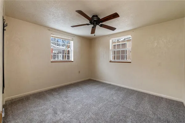 an empty room with ceiling fan and windows