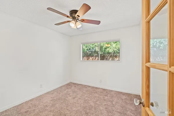 an empty room with windows and ceiling fan