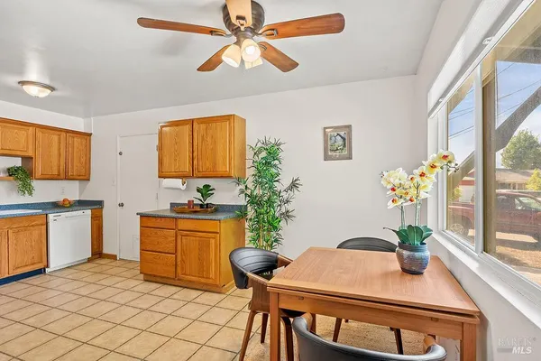 a kitchen with stainless steel appliances a white stove top oven a sink a dining table and chairs