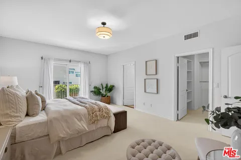 a bedroom with a large bed and a potted plant