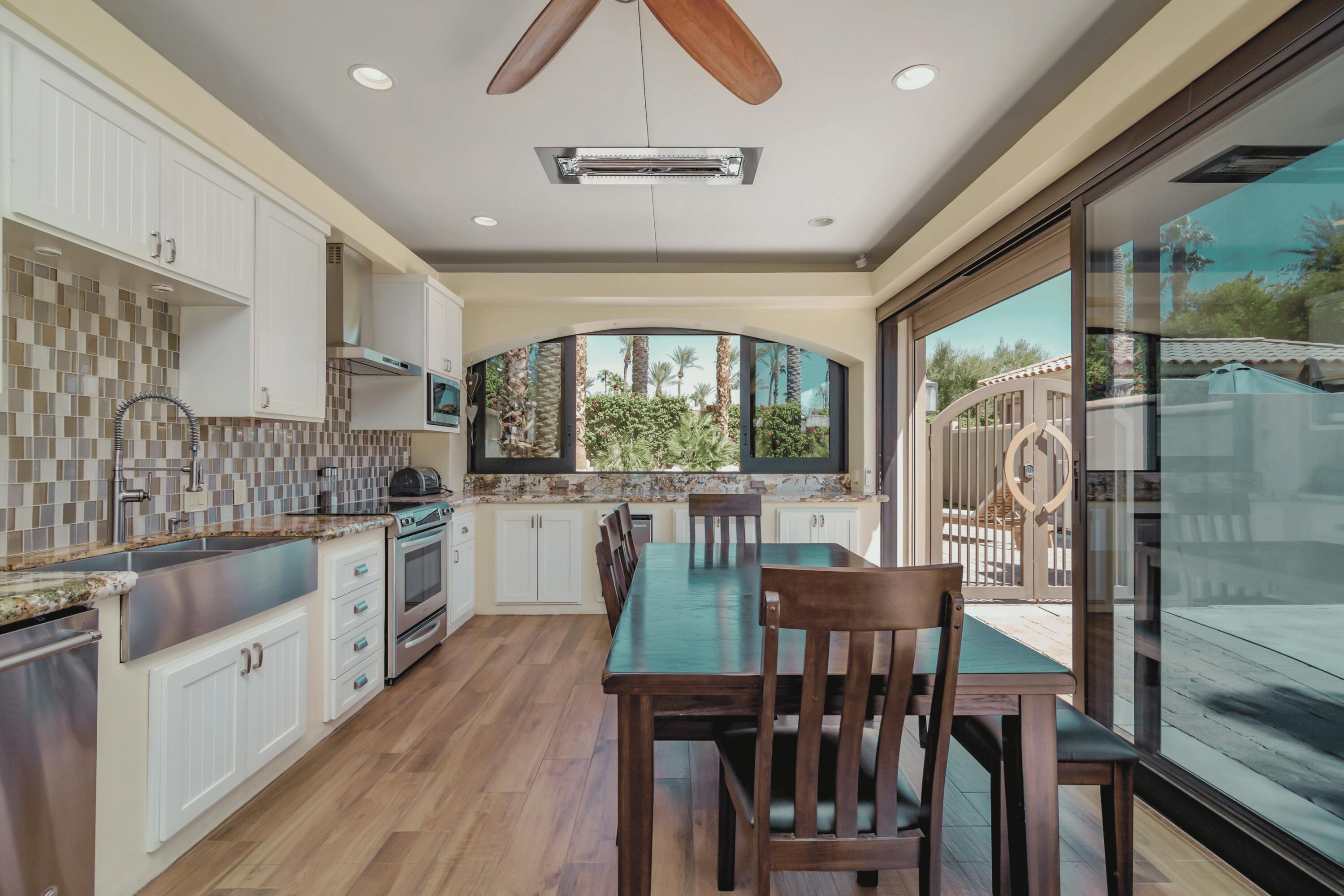 80501 Ave 48, Unit 21 Indio, CA 92201 - Photo 19 of 32 a kitchen with stainless steel appliances granite countertop a stove top oven a sink dishwasher a dining table and chairs with wooden floor