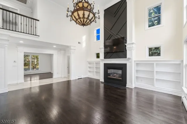 a view of an empty room with wooden floor fireplace and a window