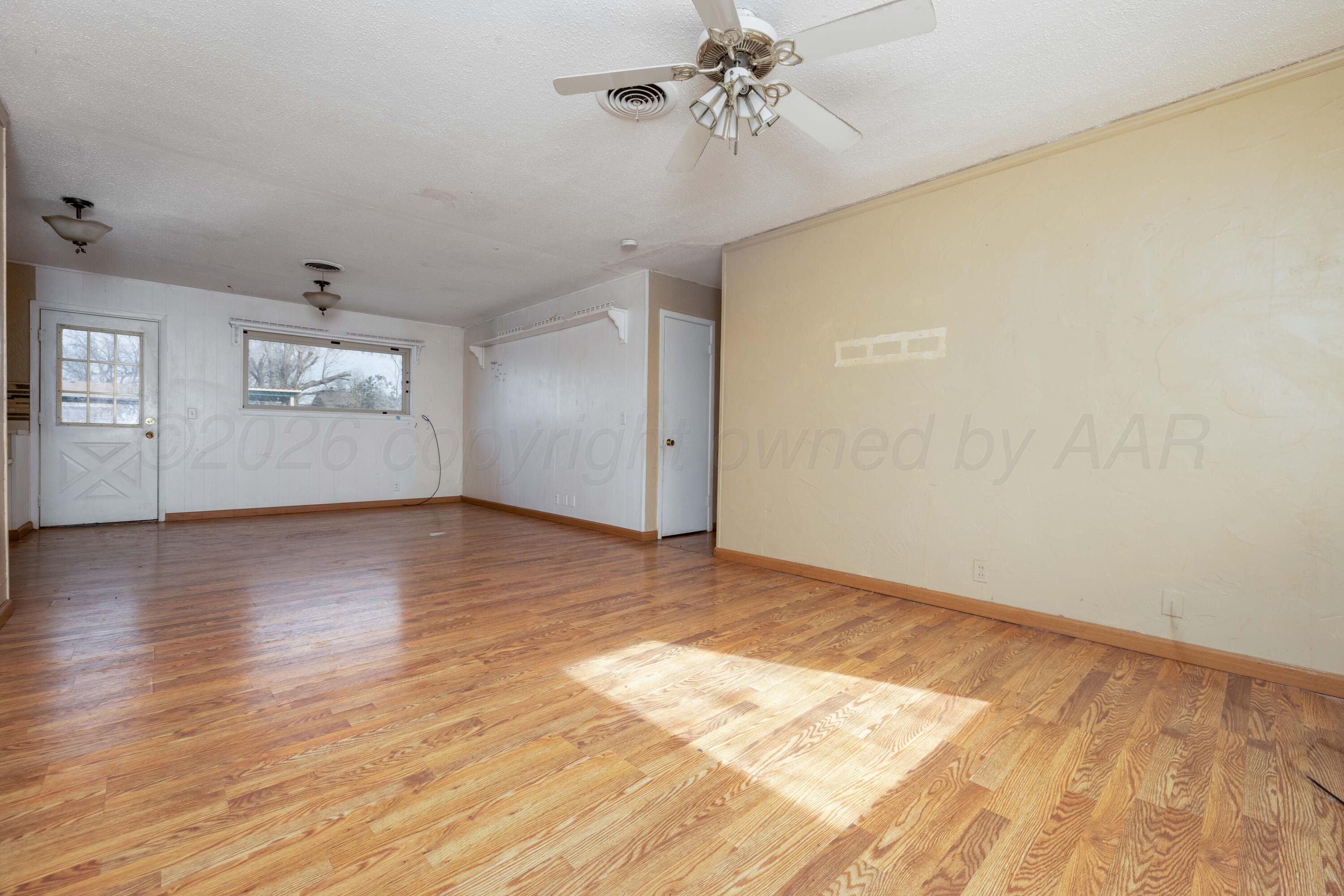 712 West Oak Street Dimmitt, TX 79027 - Photo 3 of 19 an empty room with wooden floor chandelier fan and windows
