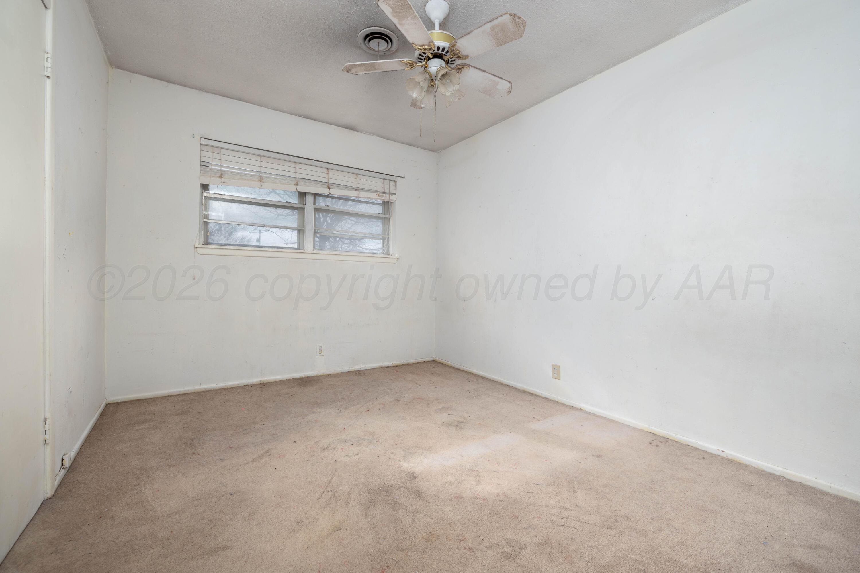 712 West Oak Street Dimmitt, TX 79027 - Photo 10 of 19 an empty room with a ceiling fan and a window