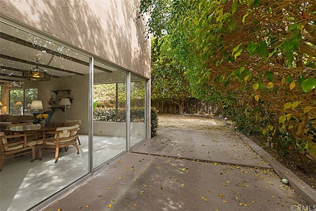 a backyard of a house with table and chairs under an umbrella