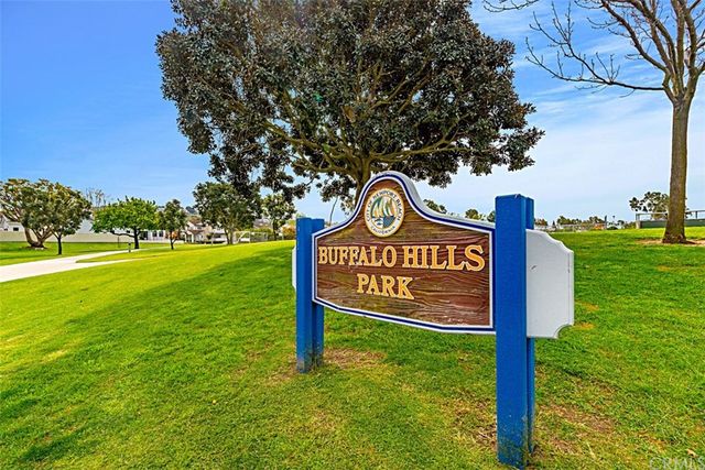 a yard with lots of trees and buildings in the background