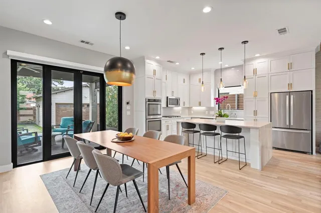 a kitchen with stainless steel appliances a dining table chairs a refrigerator and a stove