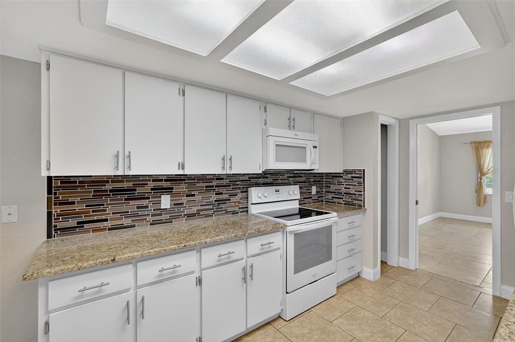 3025 Whitewood Avenue Spring Hill, FL 34609 - Photo 38 of 53 a kitchen with granite countertop white cabinets and white appliances
