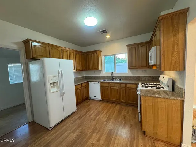 a kitchen with a refrigerator a sink dishwasher stove and wooden cabinets