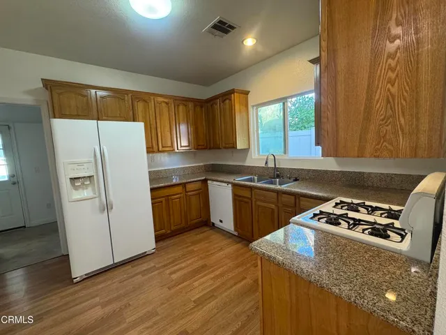 a kitchen with granite countertop a sink appliances a window and a counter top space