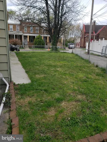 a view of a yard in front of a brick house with a large tree