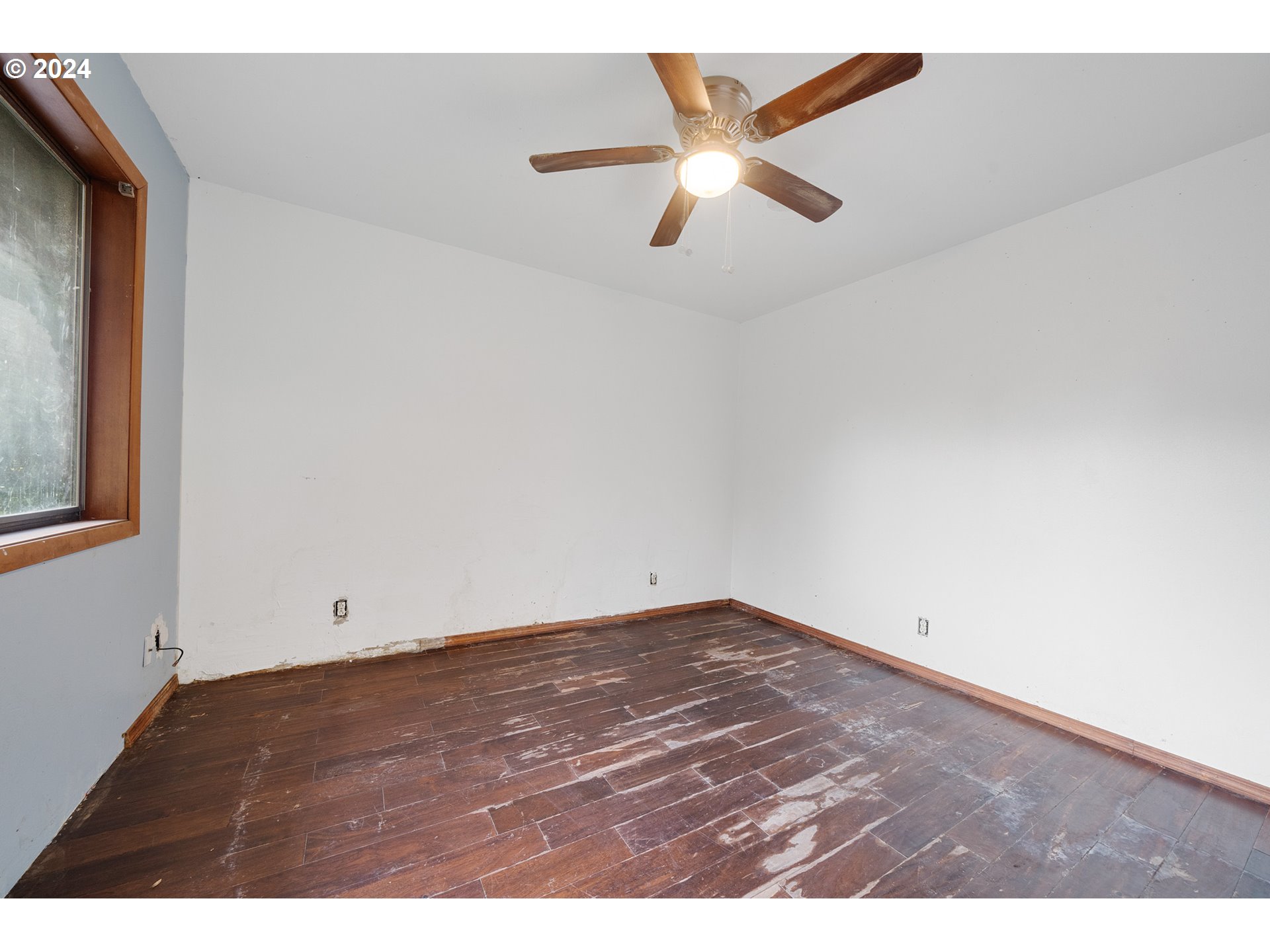 15555 Trask River Road Tillamook, OR 97141 - Photo 13 of 30 an empty room with a ceiling fan and wooden floor