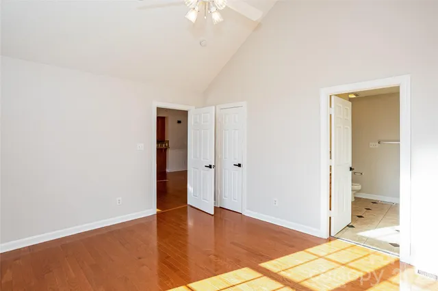 a view of an empty room with wooden floor and a bathroom