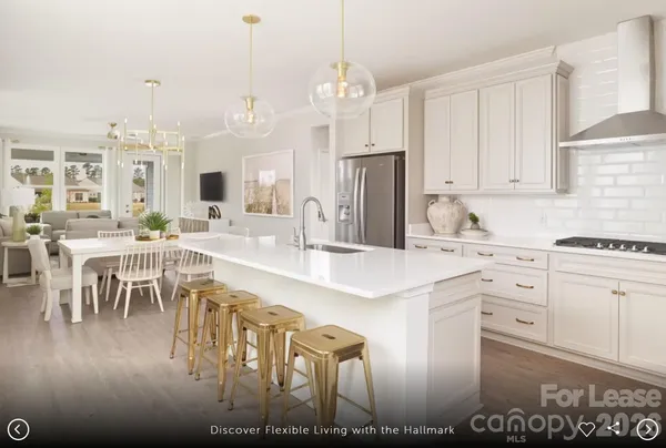 a kitchen with stainless steel appliances kitchen island granite countertop a stove a sink a refrigerator and white cabinets with wooden floor