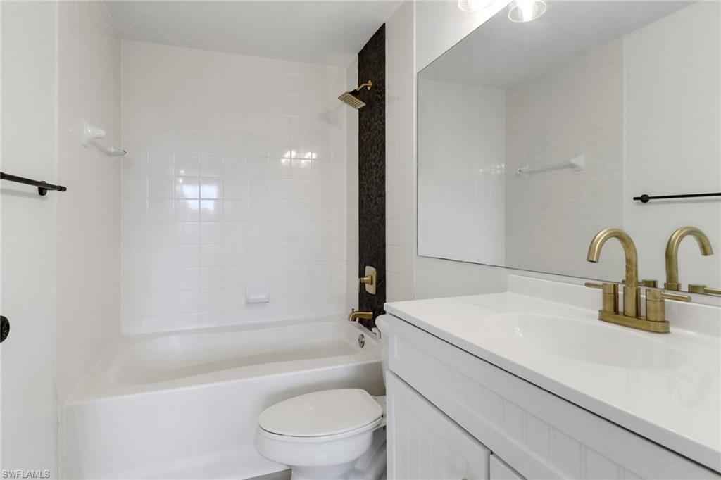 1190 Reserve Way, Unit 206 Naples, FL 34105 - Photo 15 of 35 a bathroom with a granite countertop sink a toilet and bathtub